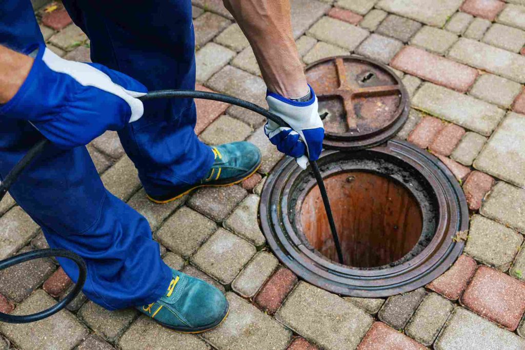 Man cleaning a sewer drain with hot water jetting machine