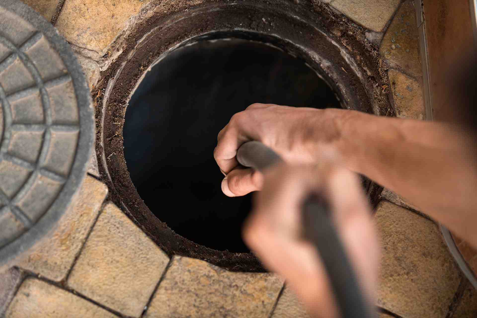 Close up on main inserting hose for hot water jetting down sewer pipe